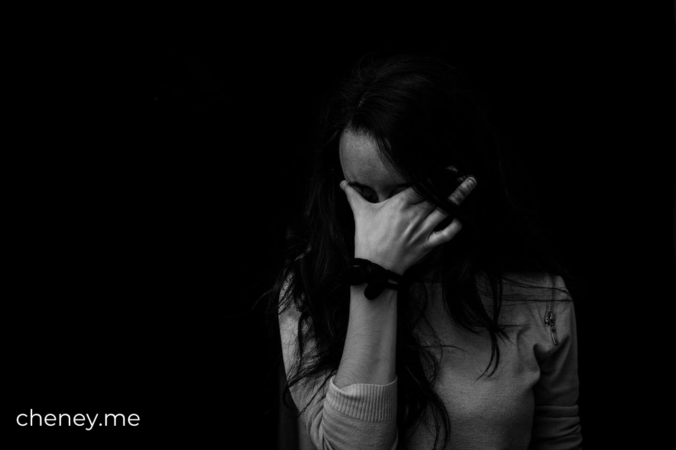 Woman standing and covering her face with her hand like she's upset about something and doesn't want to face it