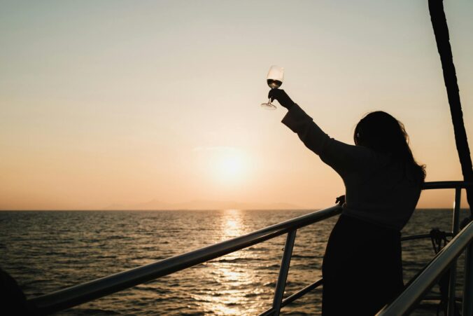 woman with drink sailing at sunset